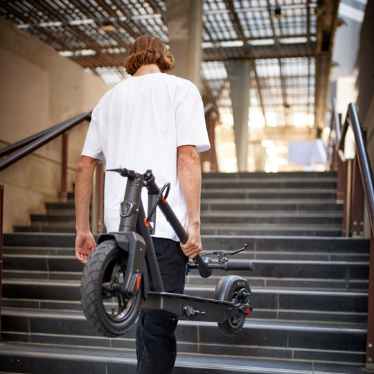 young man carrying a blvd elite electric scooter up stairs